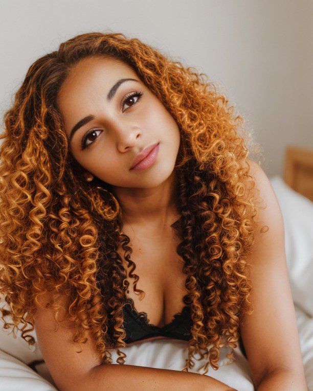 Vinfluencer Zuri Ames exudes calm elegance, her curly golden hair framing her serene, confident expression.