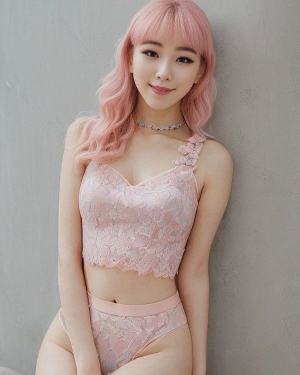 Pastel pink-haired virtual influencer Suji Boo in lace, exuding confidence against a light background.