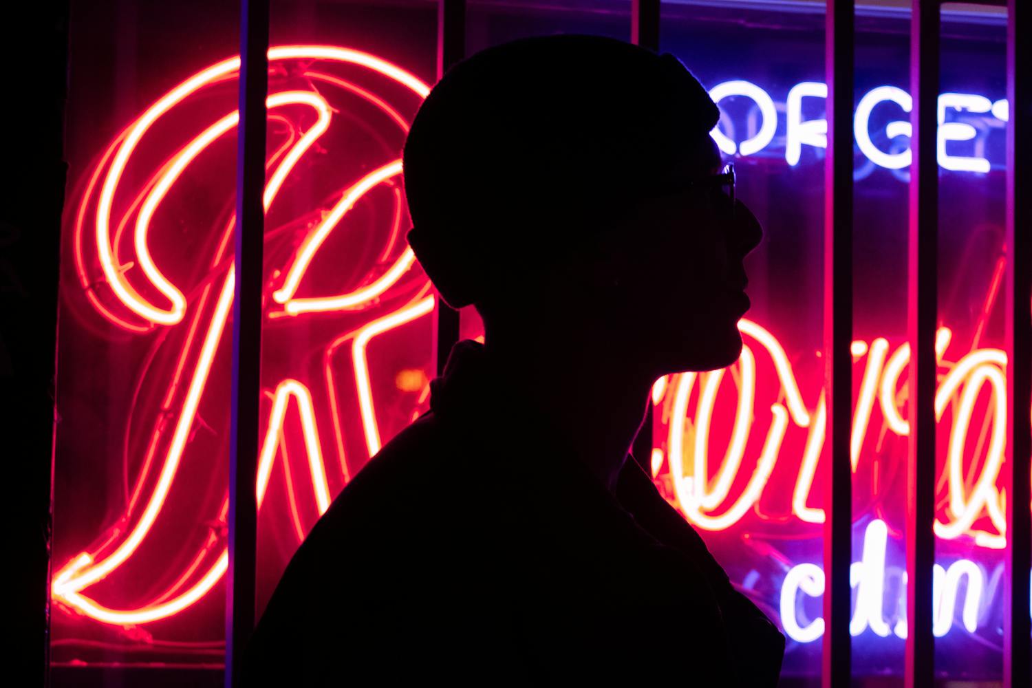 Silhouette of a person against neon signs at night, evoking the psychology of virtual influencers