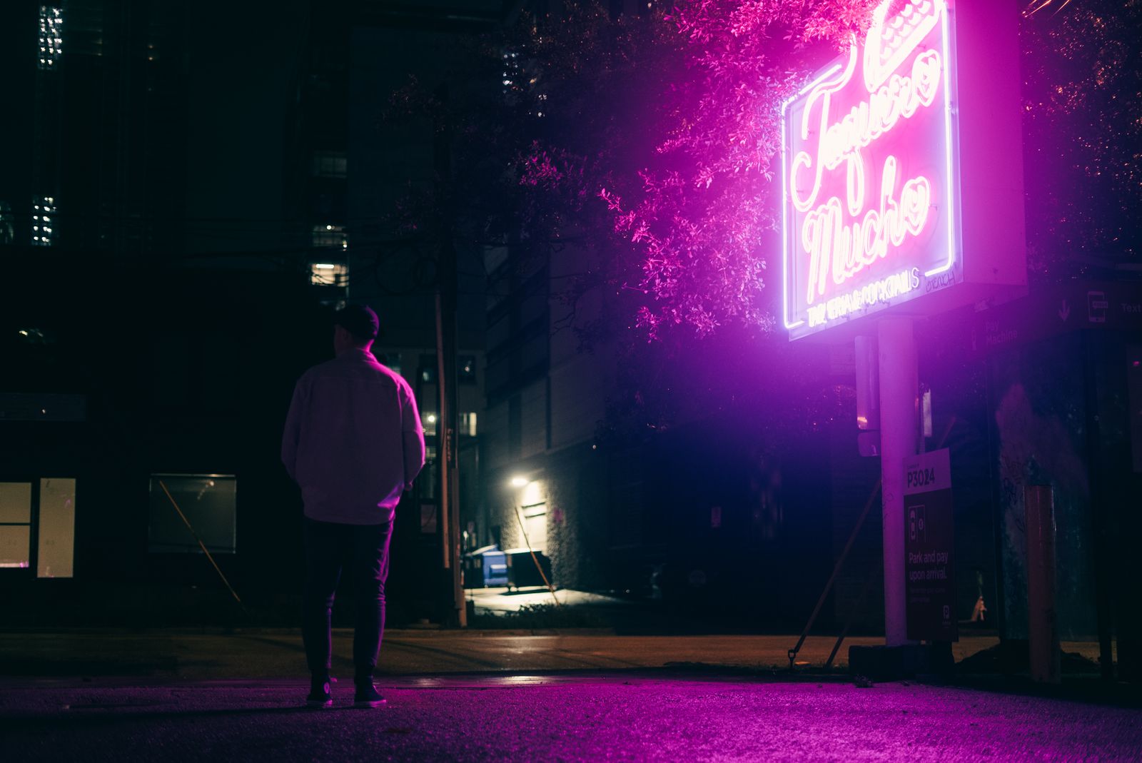 Lone figure under a pink neon street sign at night, evoking a virtual influencer vs AI companion contrast
