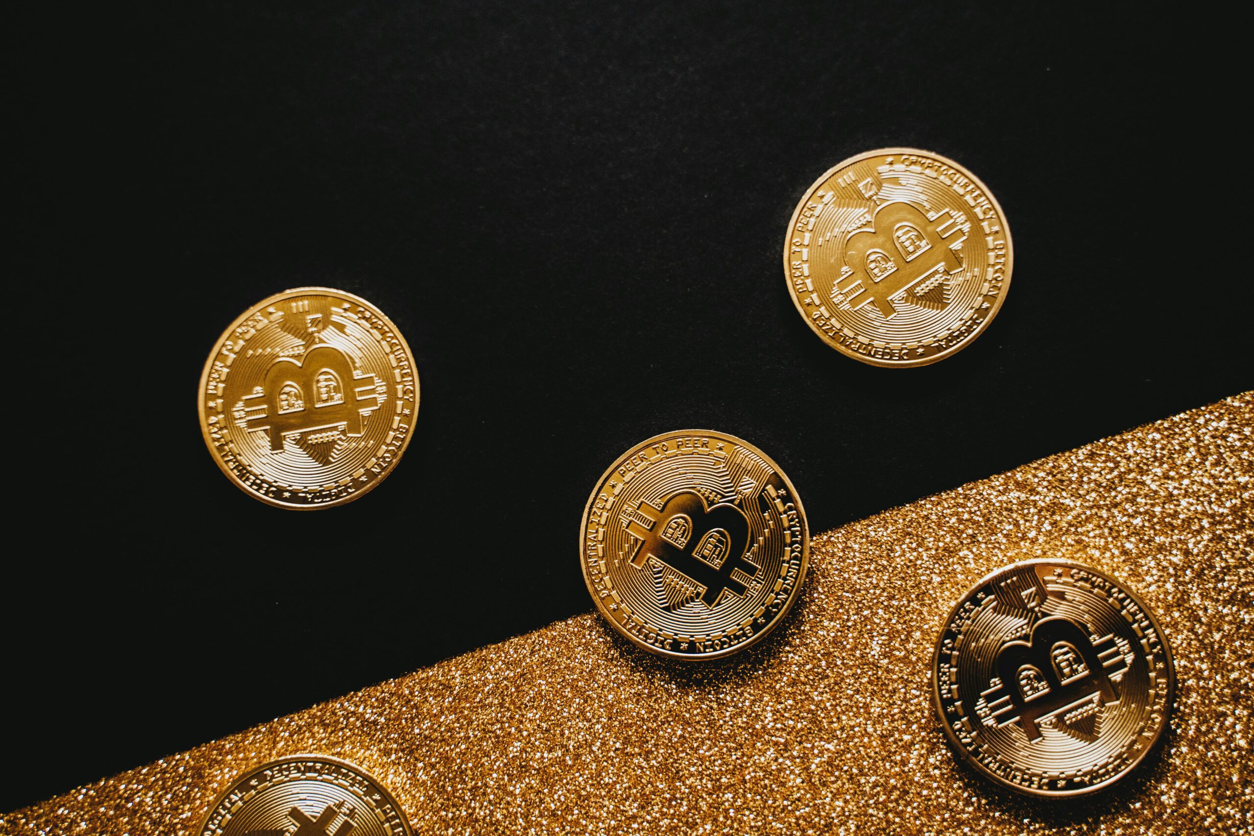 Gold Bitcoin coins arranged on a dark surface, dim single light source
