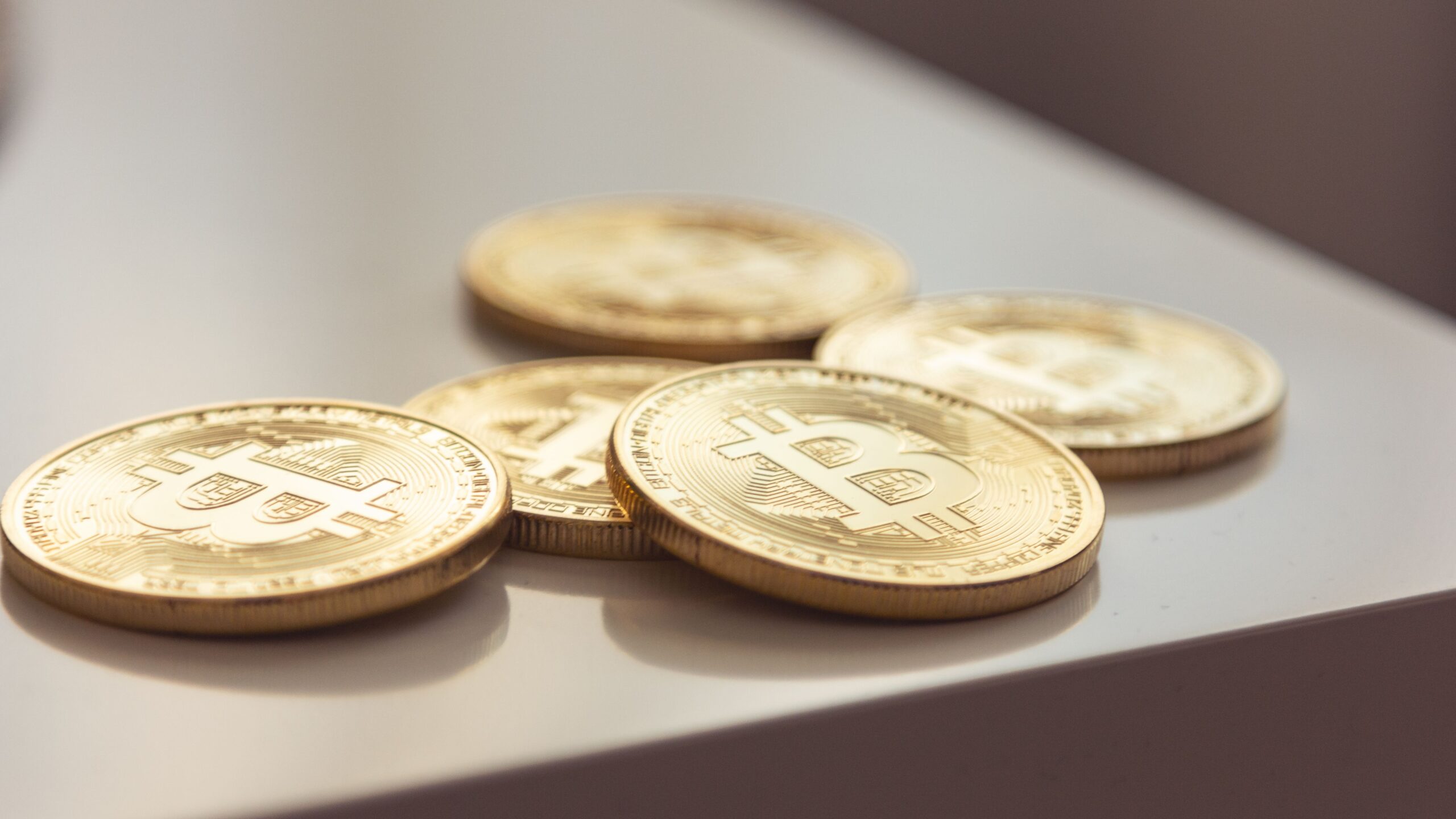 Bitcoin coins on a dark surface, single low light source, monumental composition