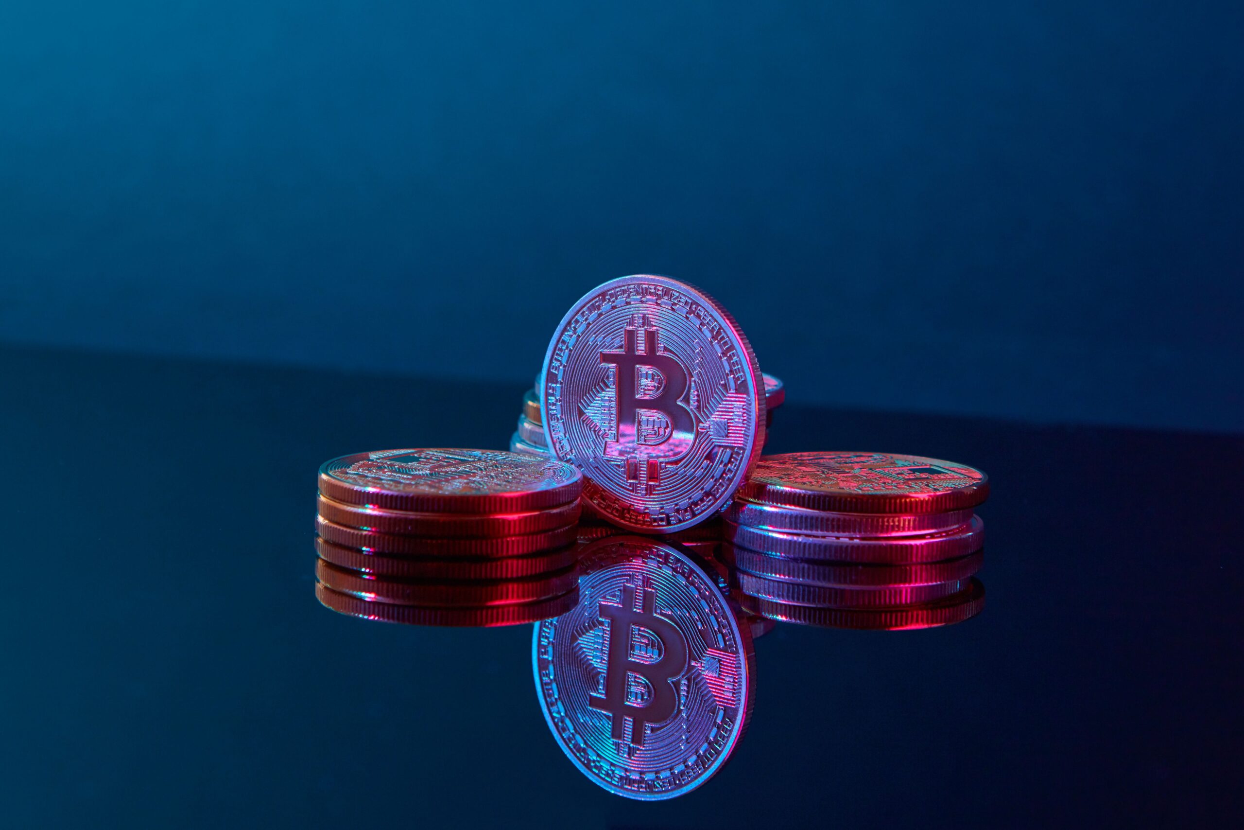 A single Bitcoin coin on a dark surface with a low warm light and a monumental composition