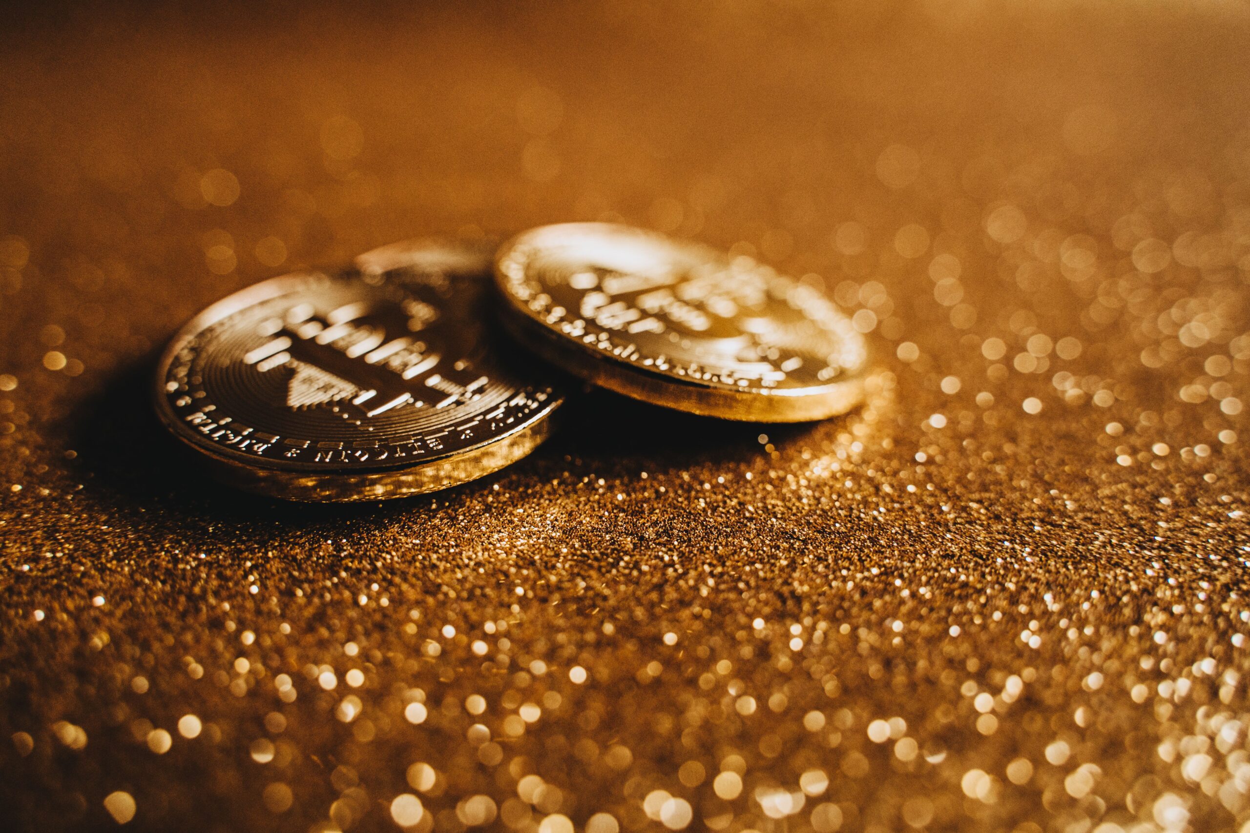 A single gold Bitcoin lit by one warm light against a dark background, like a coal glowing in shadow